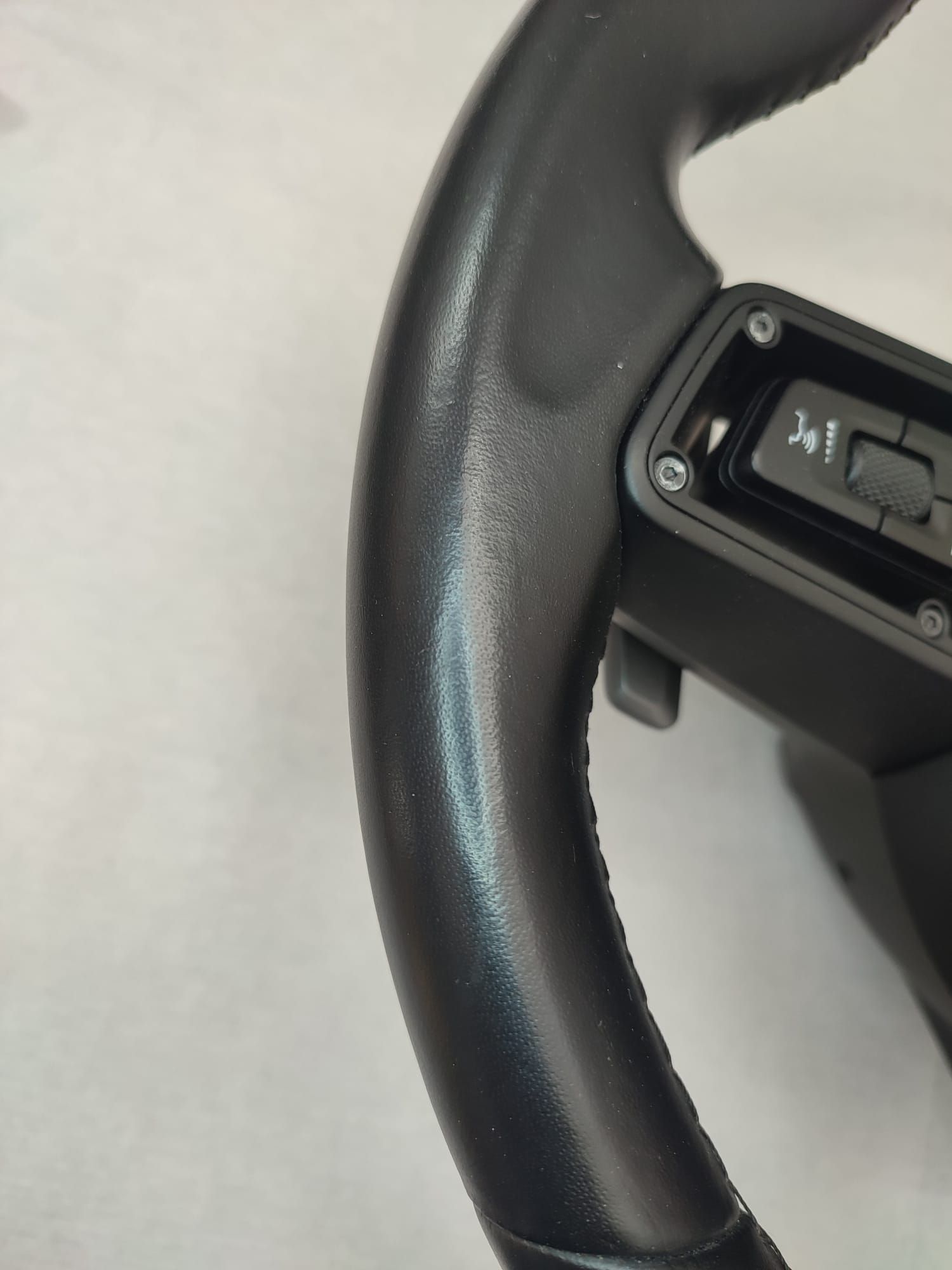 Primo piano di un volante nero con pulsanti di controllo sul lato destro.