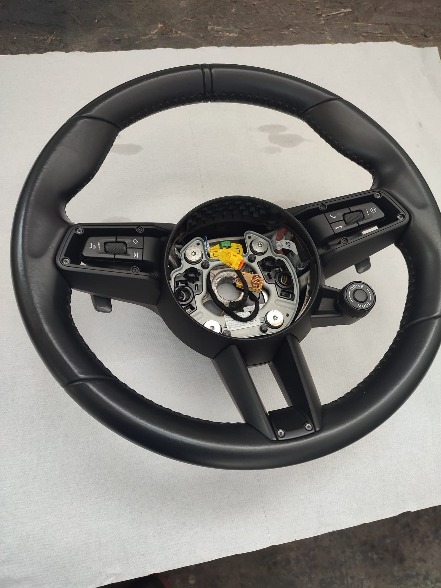 Volante nero con elettronica centrale a vista su una superficie grigio chiaro