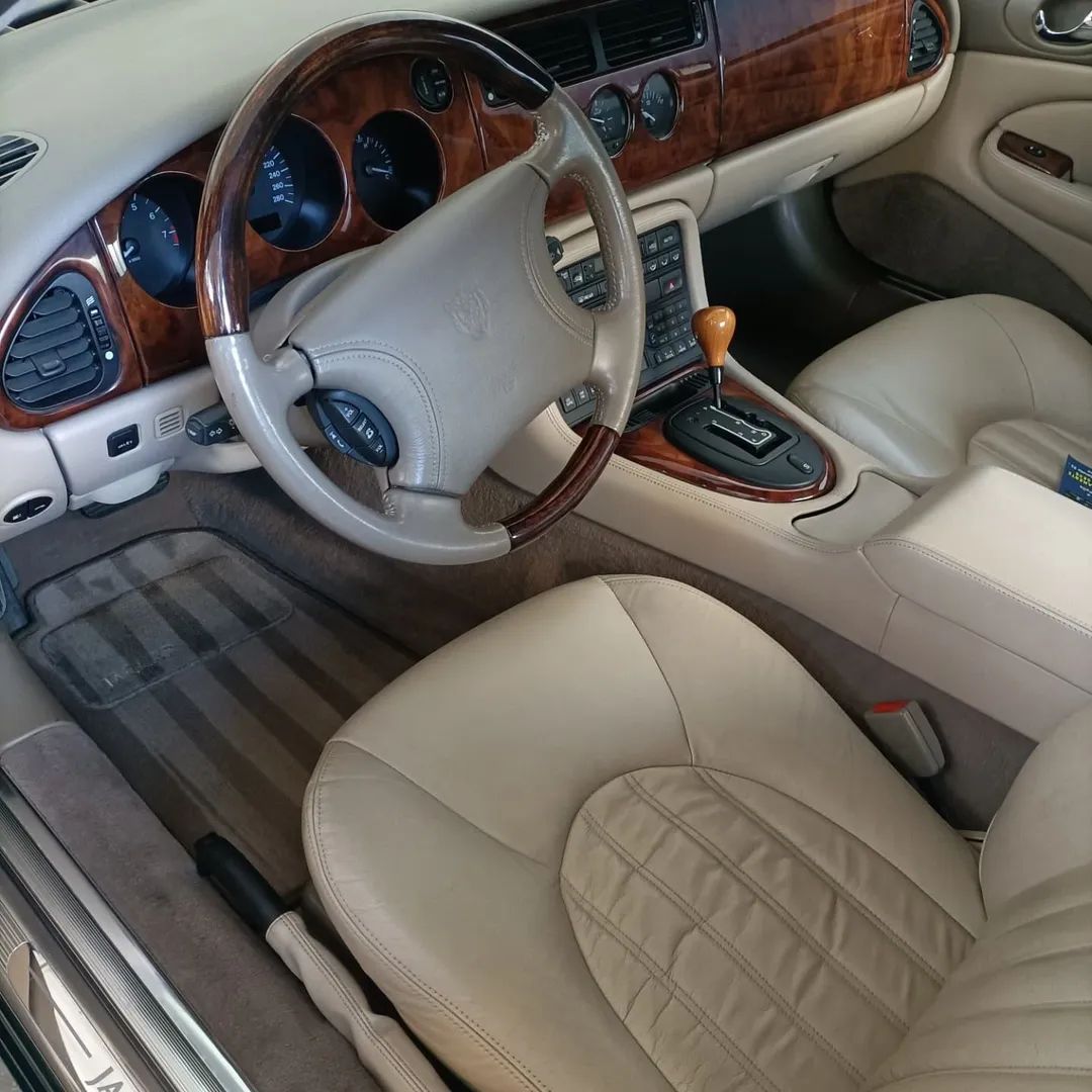 Interni di lusso beige per auto con finiture in legno, sedili in pelle e volante panoramico.