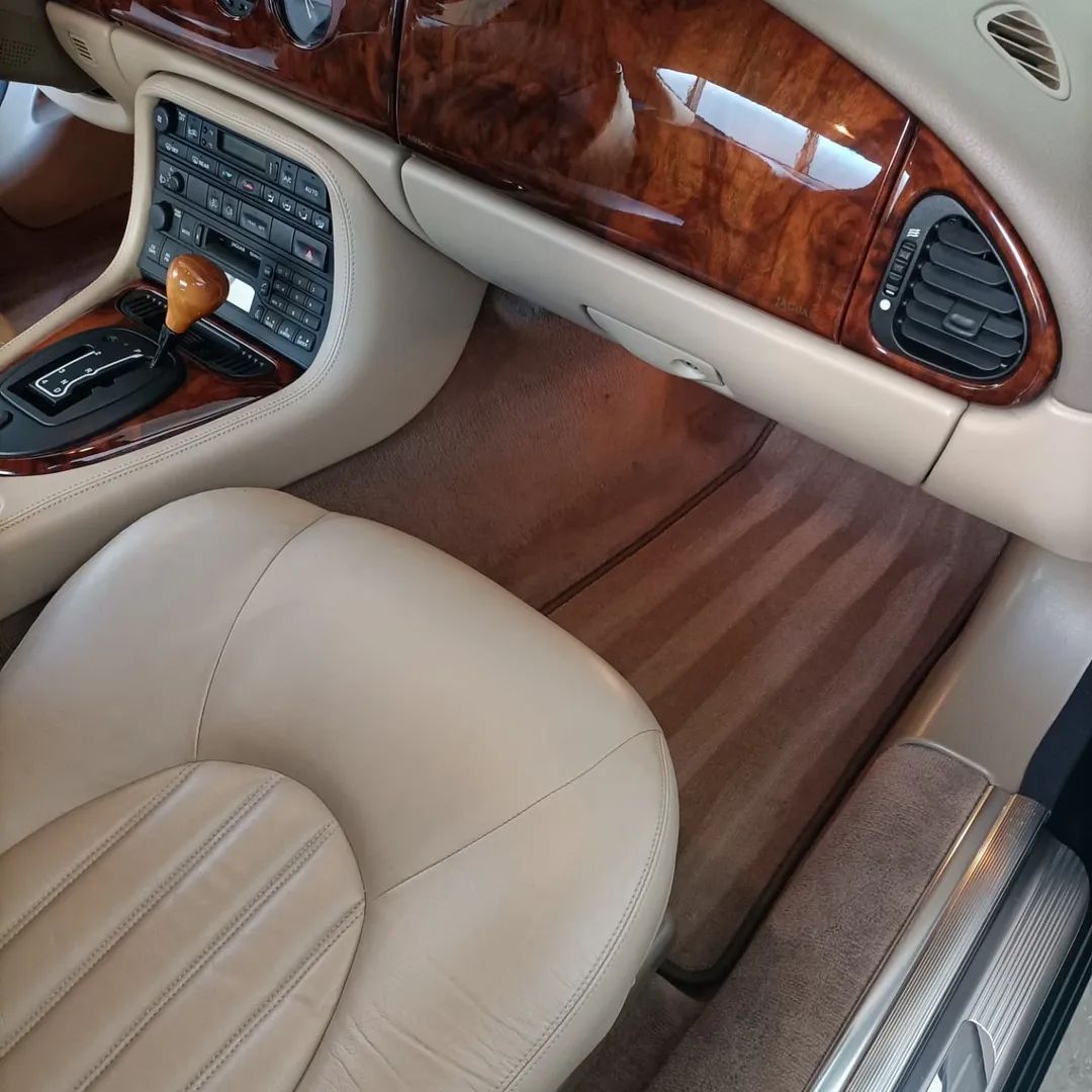 Interni di lusso con sedili in pelle beige, inserti in legno e comandi sulla console centrale.