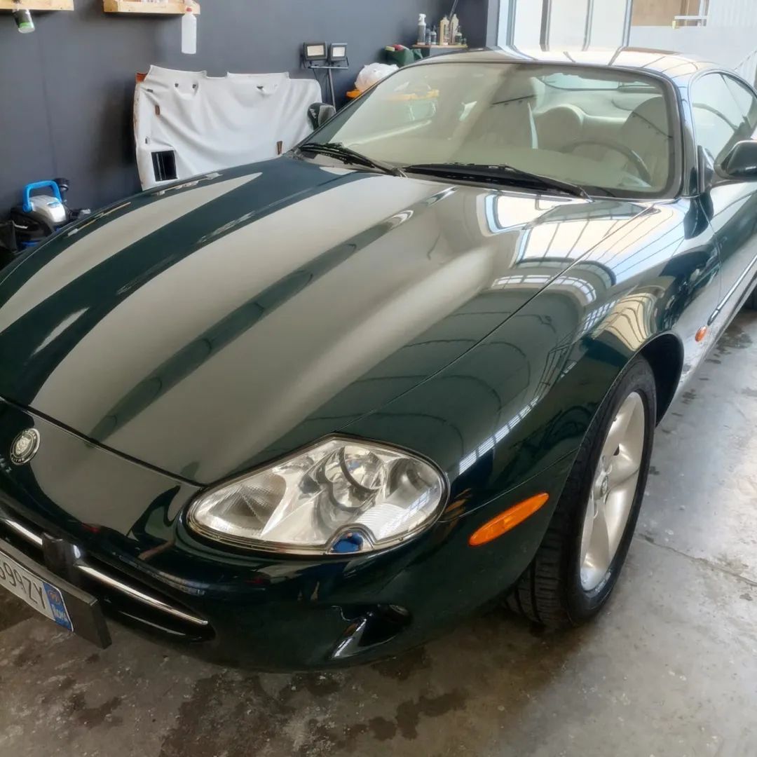 Auto sportiva verde scuro con strisce da corsa parcheggiata in un garage