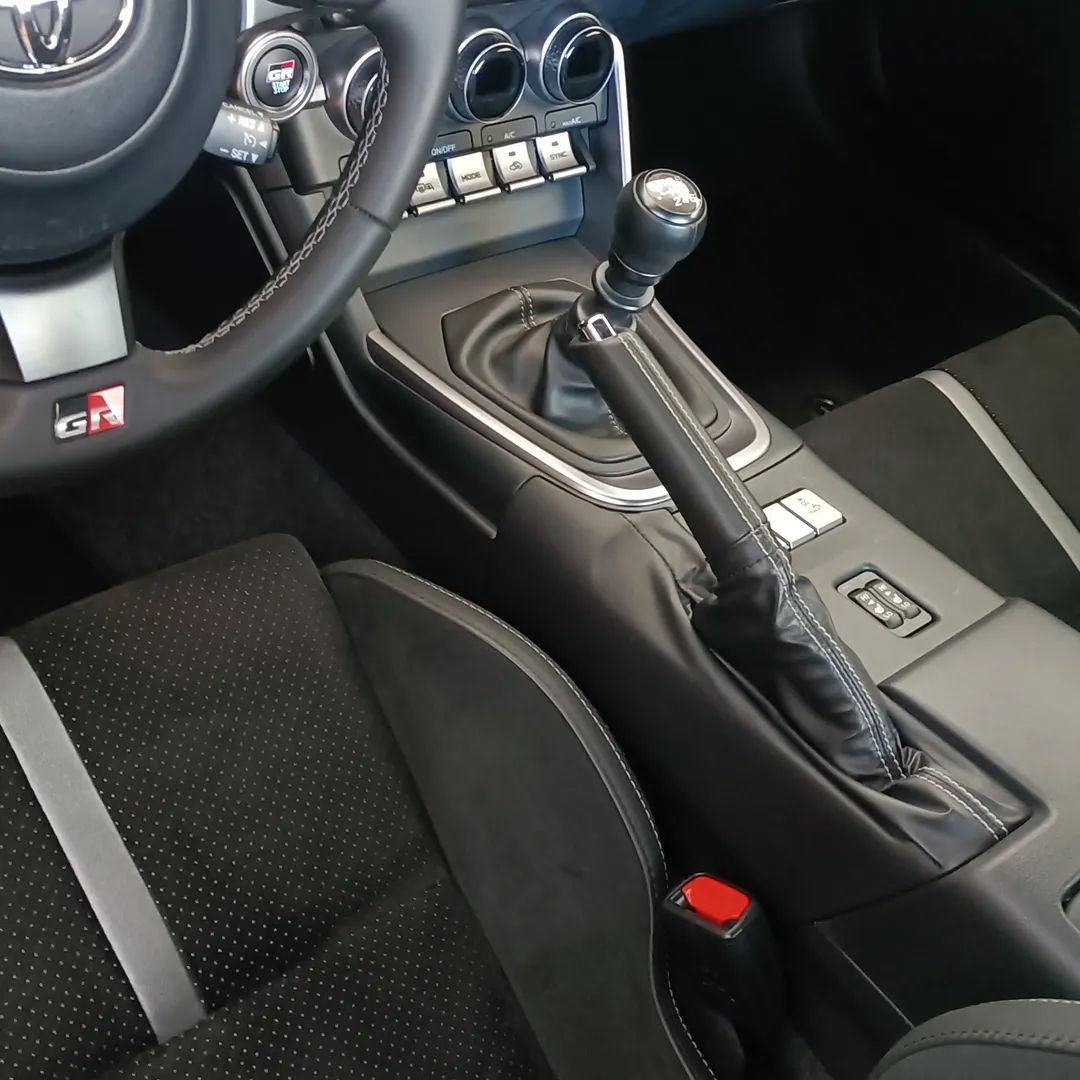 Interni dell'auto con cambio manuale, sedili neri e console centrale.