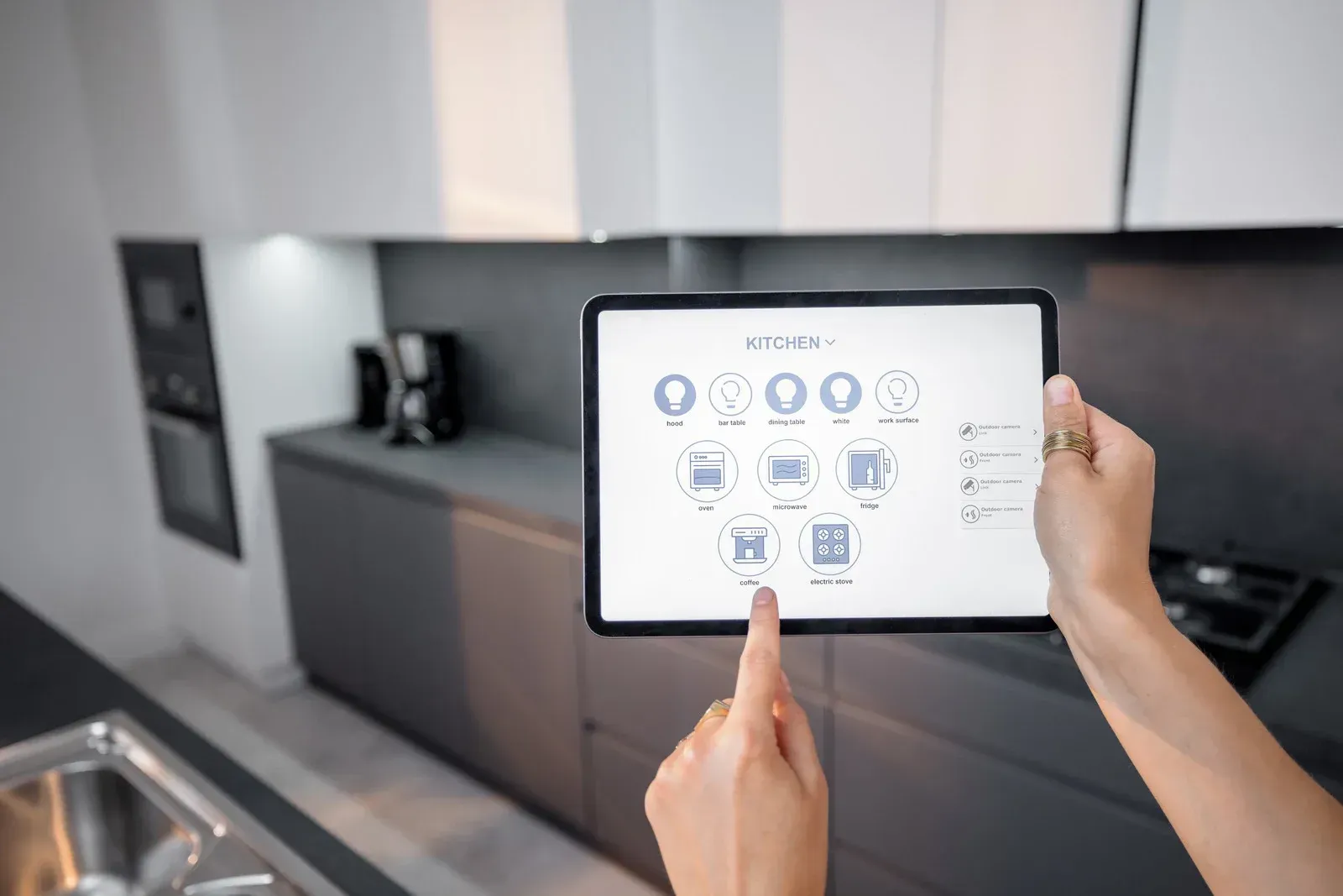 A person is holding a tablet in their hands in a kitchen.