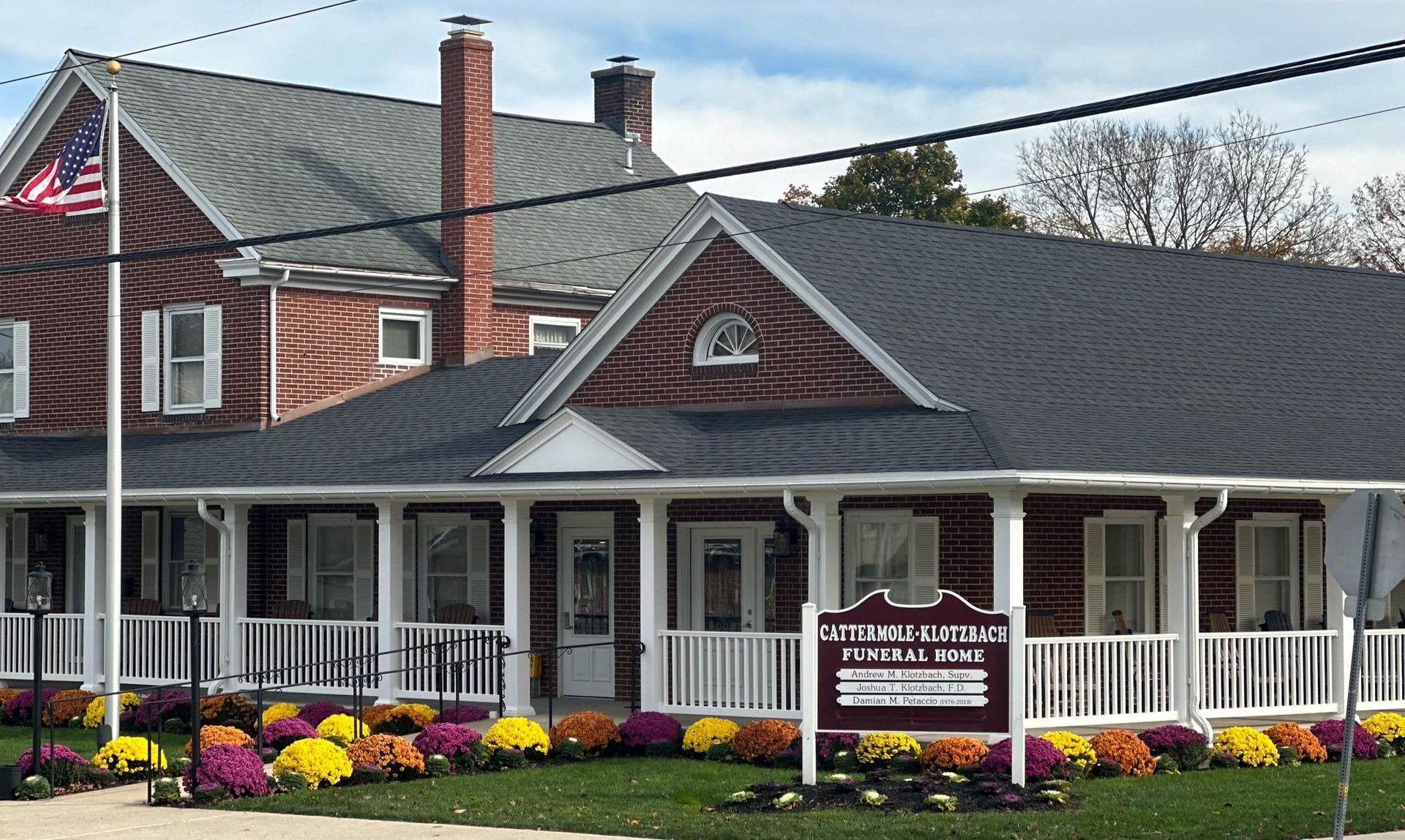 White Victorian inn with porch, red brick chimneys, and colorful flower beds