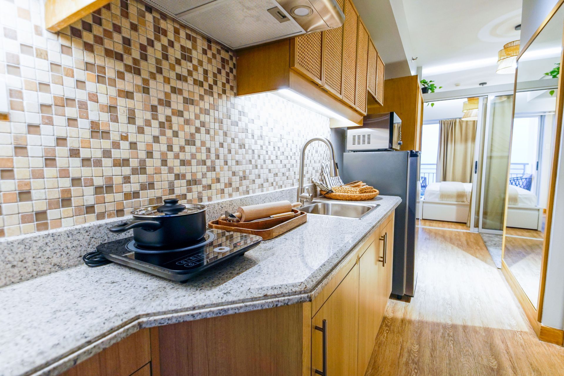 Bright modern kitchen with granite counter, stovetop, sink, fridge, and tiled backsplash