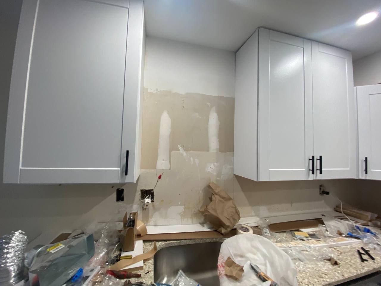 A kitchen under construction with white cabinets and a sink