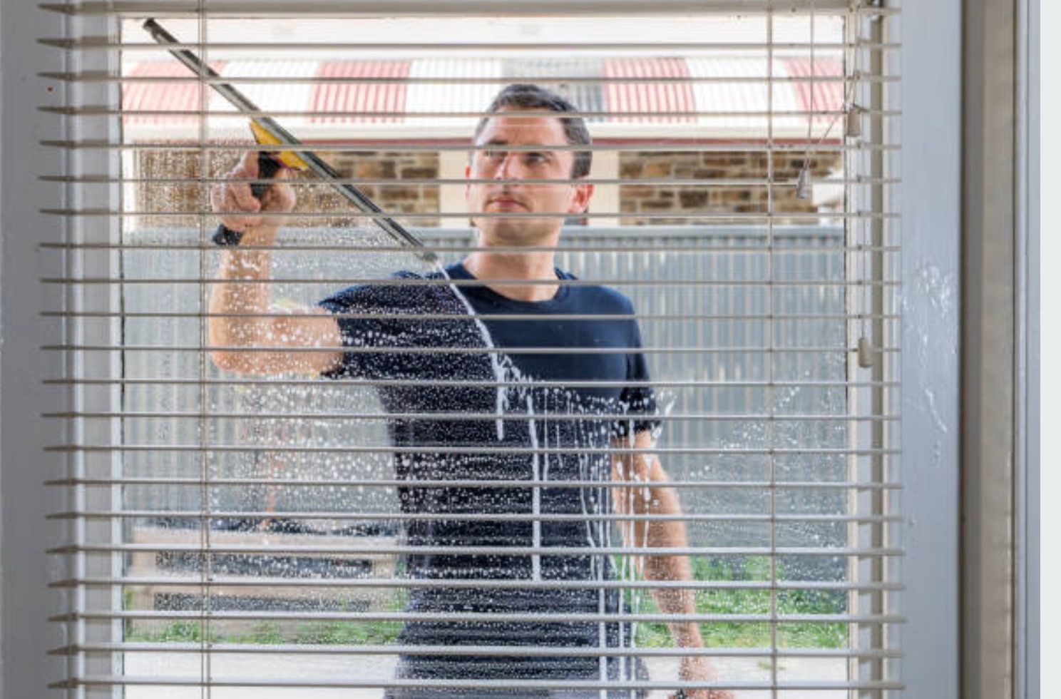A man is cleaning a window with a squeegee.