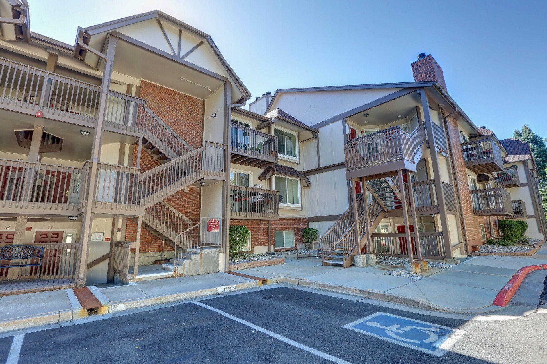 A large apartment building with stairs and a handicapped parking spot in front of it.