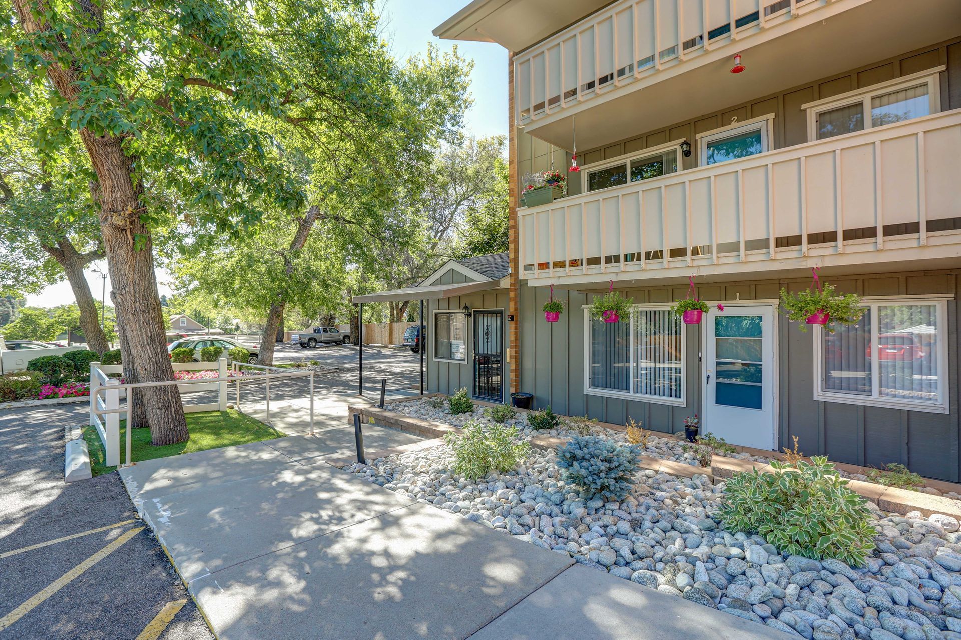A large apartment building with a walkway and a parking lot in front of it.