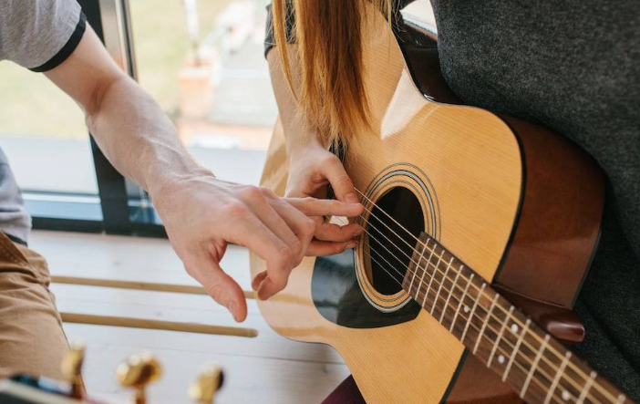 Instructor guiding proper finger placement during acoustic guitar lesson in Little Rock, Arkansas.