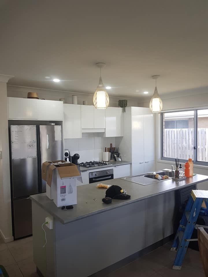 A Kitchen With White Cabinets, Stainless Steel Appliances, And A Large Island — Prowire Services In Mackay, QLD