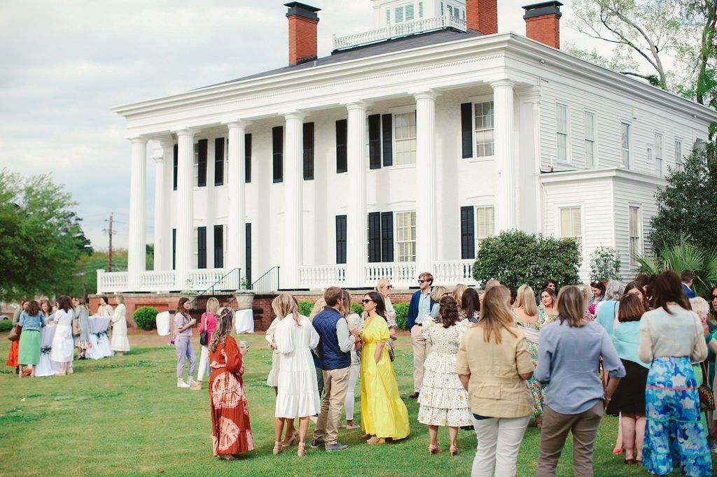 A group of people are standing in front of a large white building.