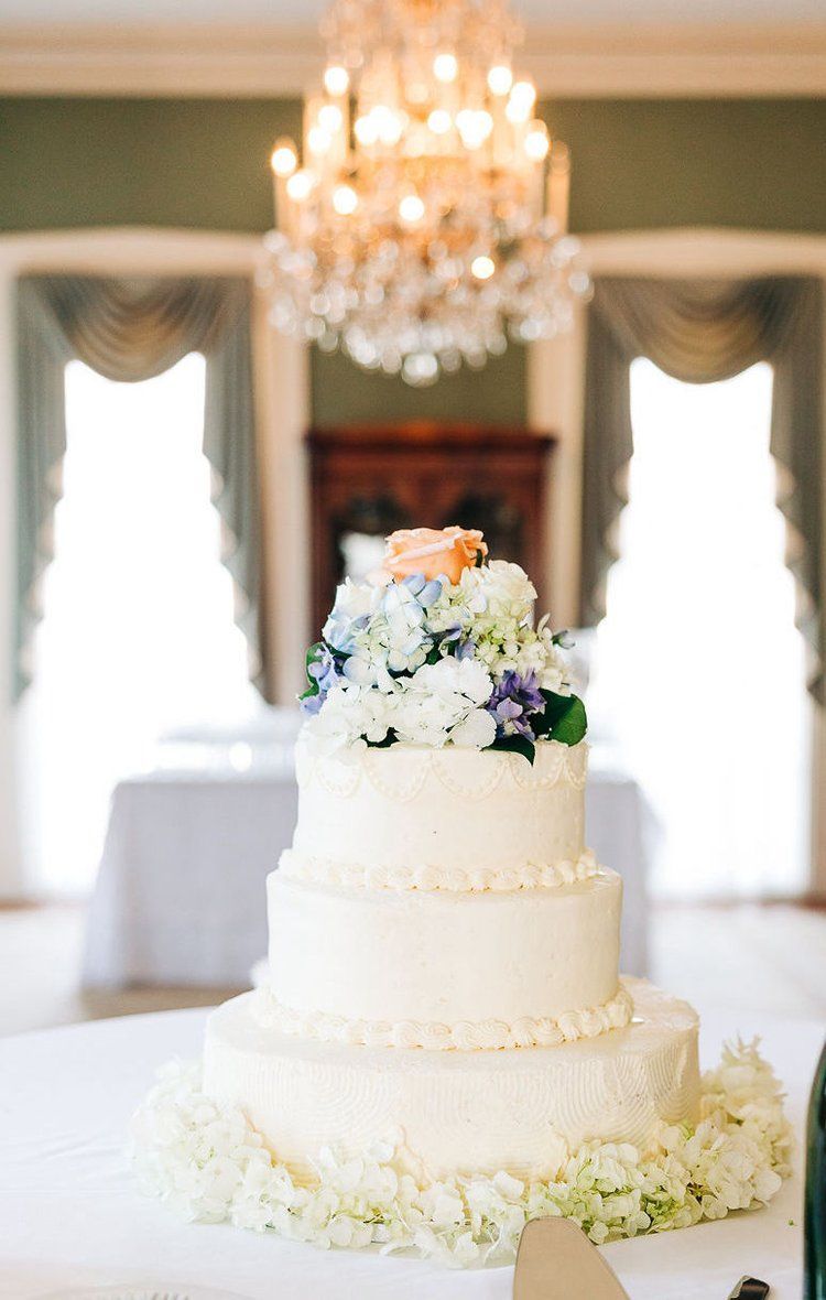 A wedding cake is sitting on a table in front of a chandelier.