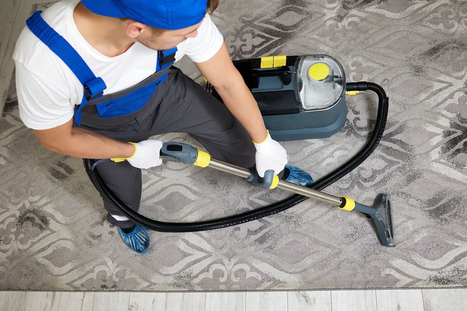 Person vacuuming a patterned carpet with a canister vacuum cleaner