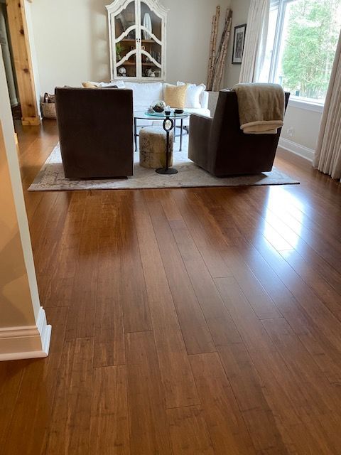 Living room with hardwood floors, two armchairs, a rug, and a bright window view