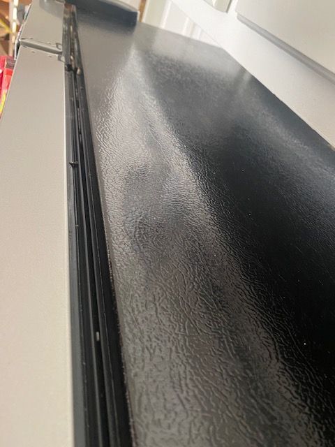Black textured countertop beside a white wall in a narrow indoor hallway