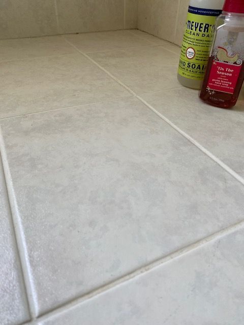 Light beige tiled floor with cleaning products in the corner