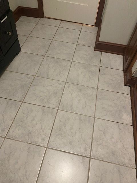 Tiled kitchen floor with beige tiles and dark wood trim near a doorway