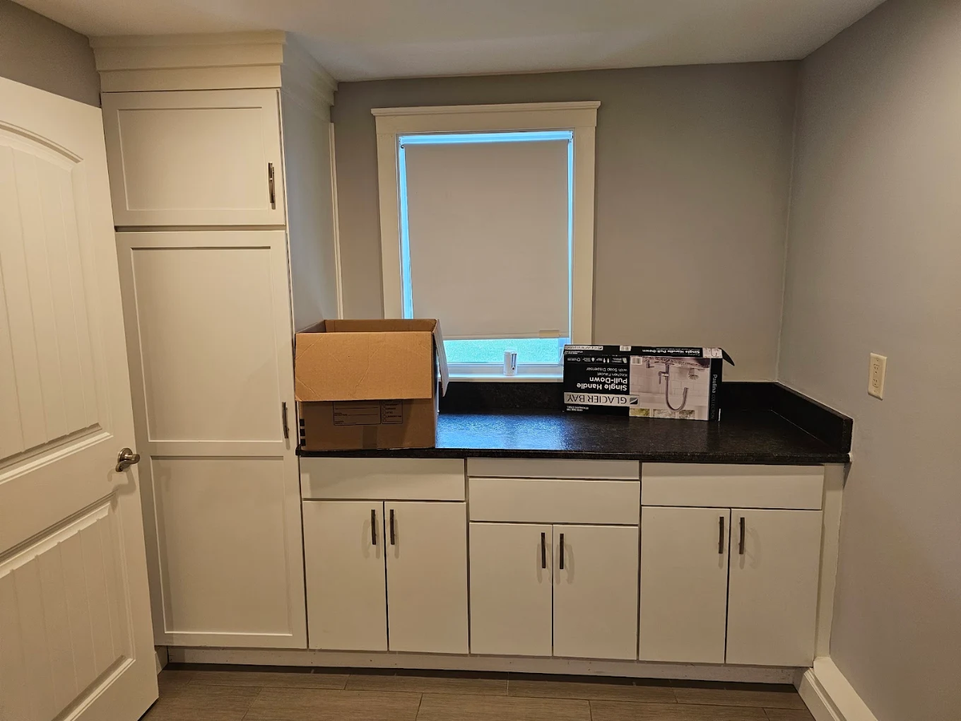 Empty bright room with hardwood floors and three windows on beige walls.