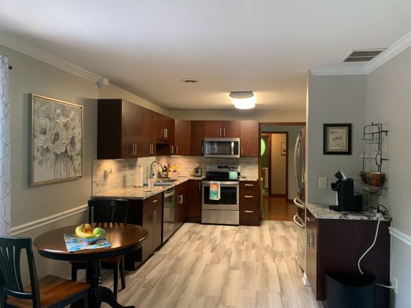 Open-concept kitchen and dining area with dark wood cabinets, stainless appliances, and a small round table.