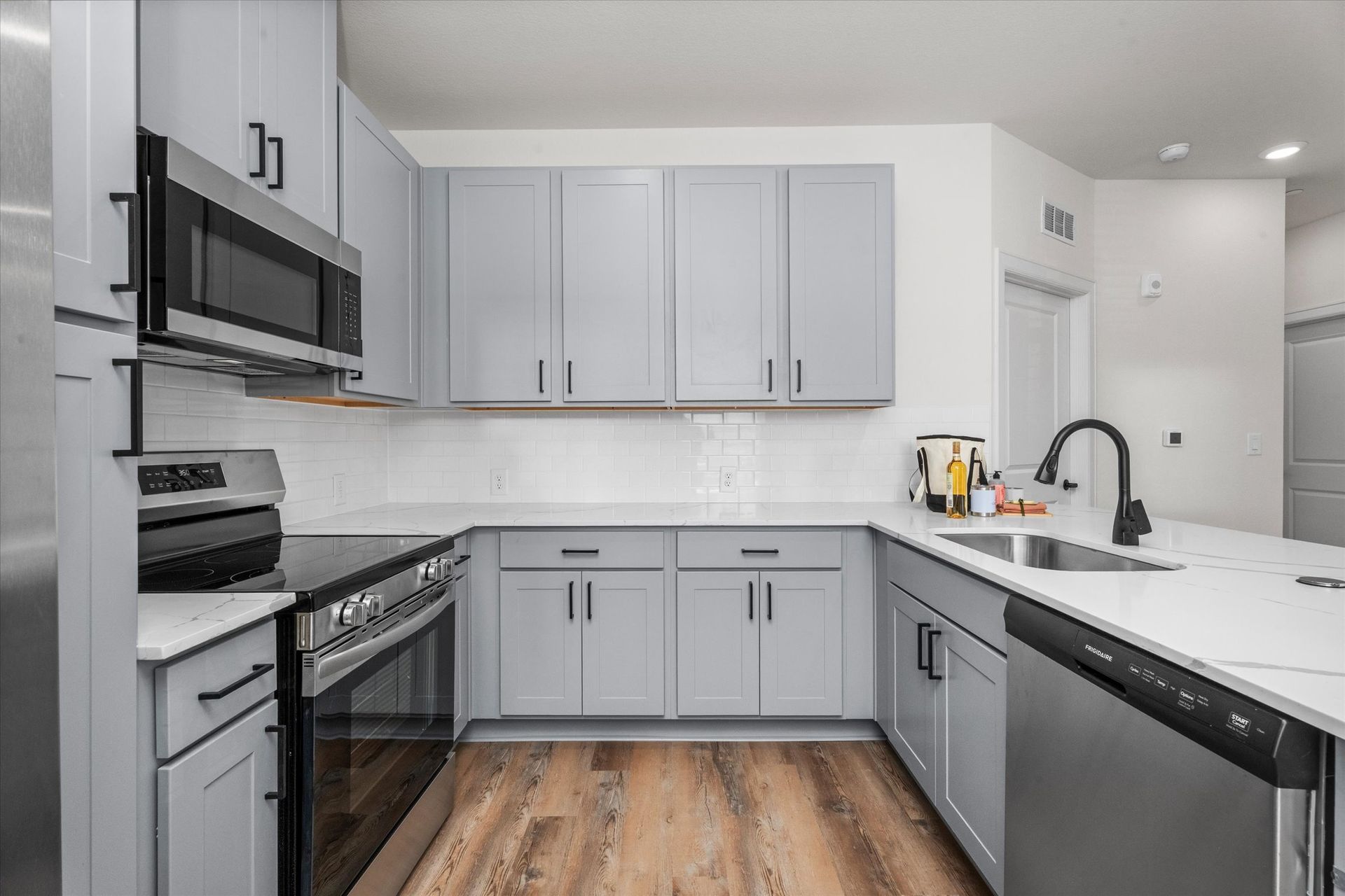 Modern apartment kitchen with gray cabinetry, quartz countertops and stainless steel appliances at Cottage Green Simpsonville