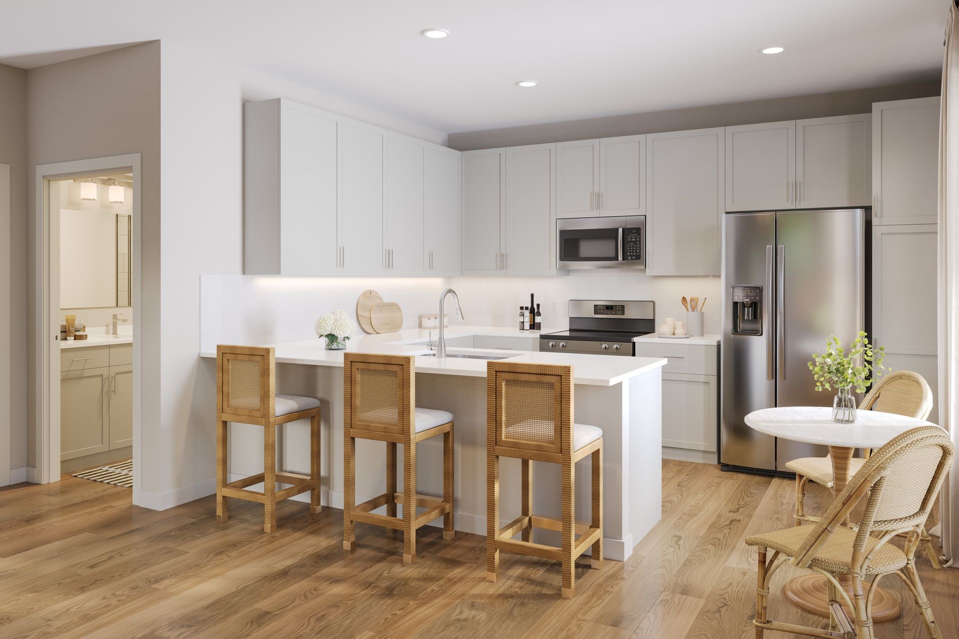 Modern white kitchen with island seating, stainless steel fridge, and warm wood floors