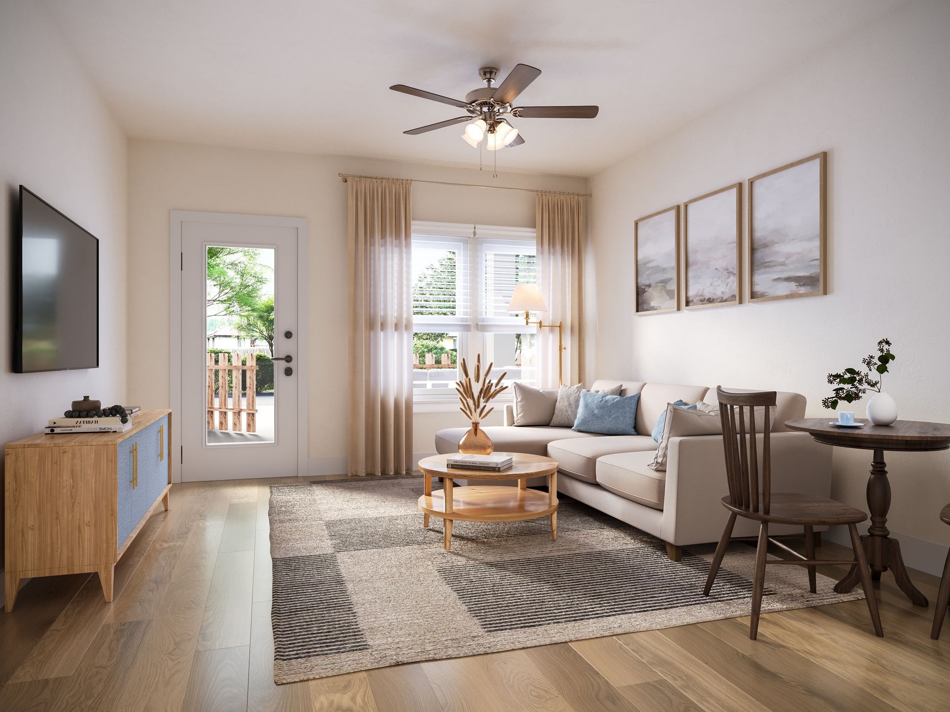 Bright living room with beige sofa, coffee table, patterned rug, wall art, and balcony doors with sheer curtains