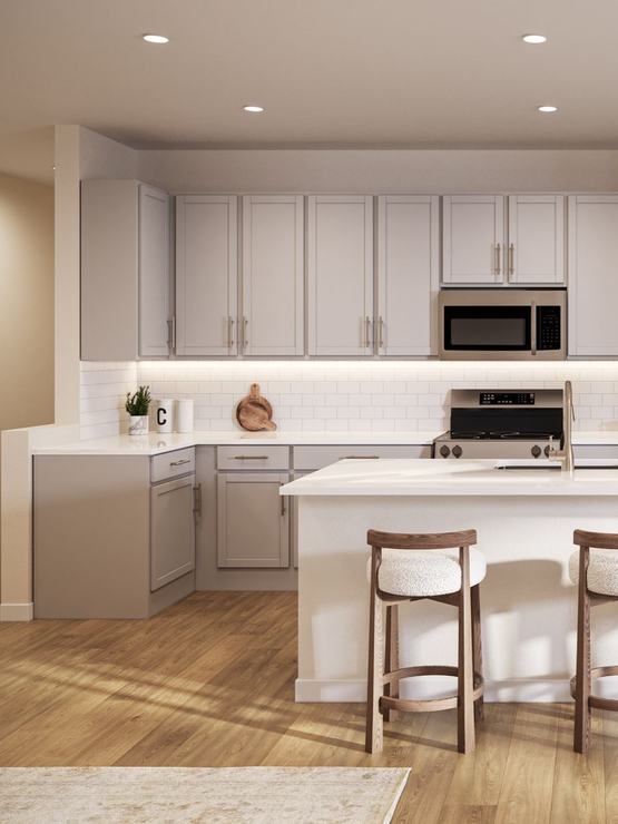 Modern white kitchen with island, four stools, stainless appliances, and light wood floors.