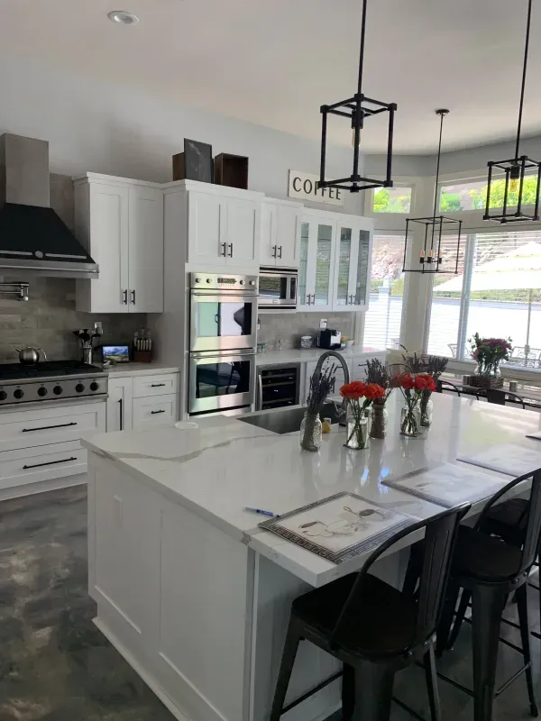 A modern kitchen with white cabinets, a large center island, marble-style countertops, and pendant lighting.