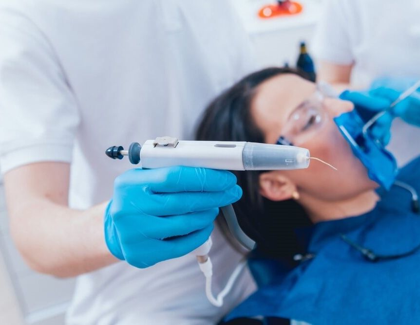 A Dentist is Holding a Syringe in Front of a Patient's Mouth — Bytes of Byron–Bio Holistic Dentistry in Byron Bay, NSW