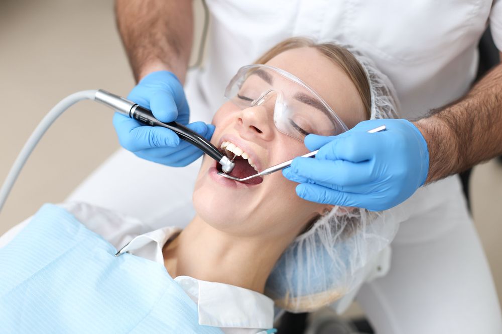 A Woman is Sitting in a Dental Chair Getting Her Teeth Examined — Bytes of Byron–Bio Holistic Dentistry in Byron Bay, NSW