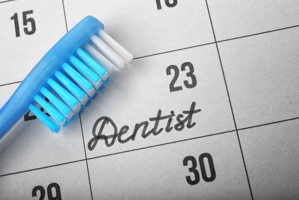 A Blue Toothbrush Rests on a Calendar That Says Dentist on It — Bytes of Byron–Bio Holistic Dentistry in Byron Bay, NSW