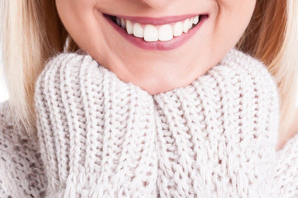 A Close Up of a Woman Wearing a Sweater and Smiling — Bytes of Byron–Bio Holistic Dentistry in Byron Bay, NSW