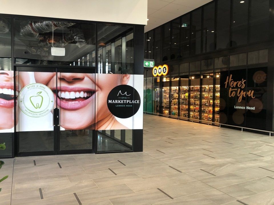 A Store Front With a Picture of a Woman 's Smile on the Window — Bytes of Byron–Bio Holistic Dentistry in Lennox Head, NSW
