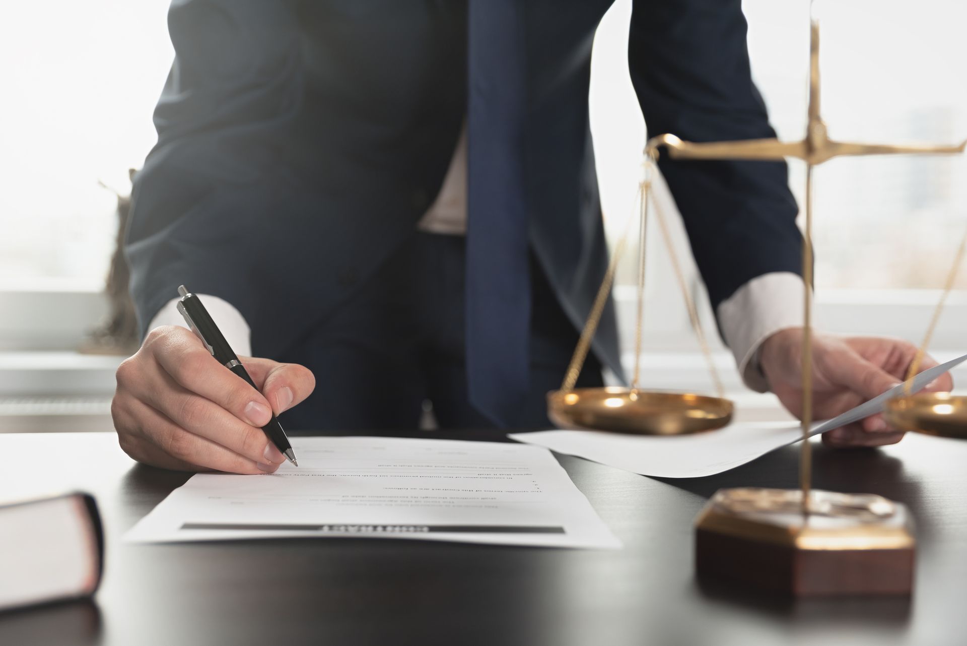A man in a suit and tie is writing on a piece of paper.