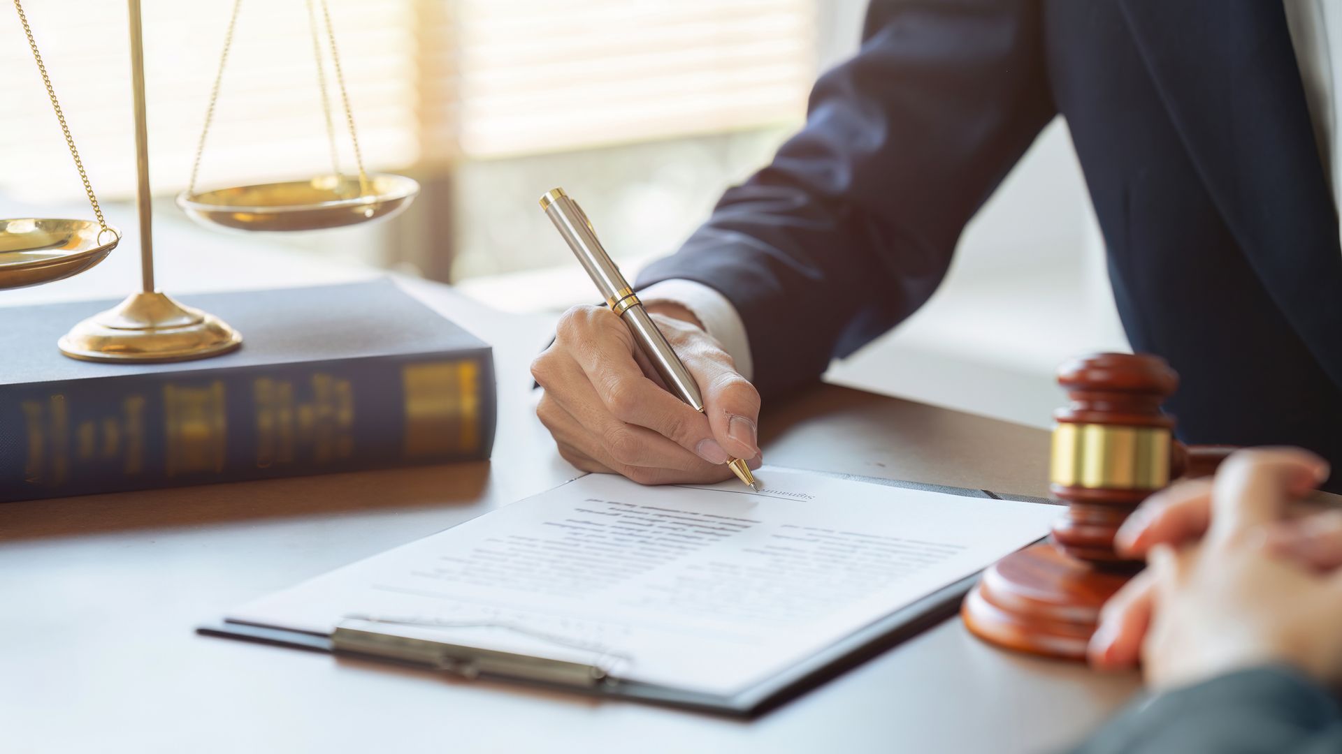 A lawyer is writing on a clipboard in front of a judge 's gavel.