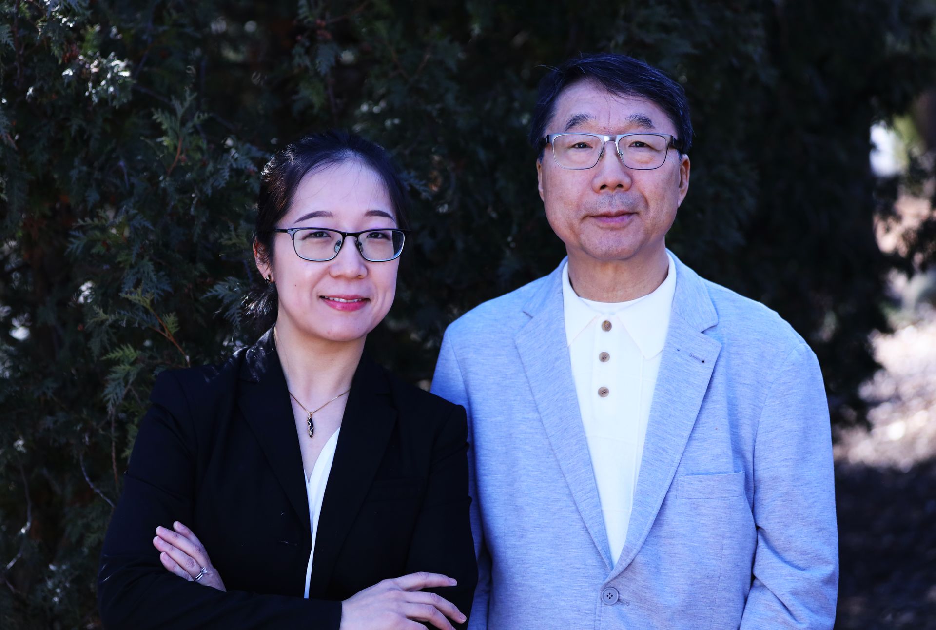 A man and a woman are standing next to each other in front of a tree.