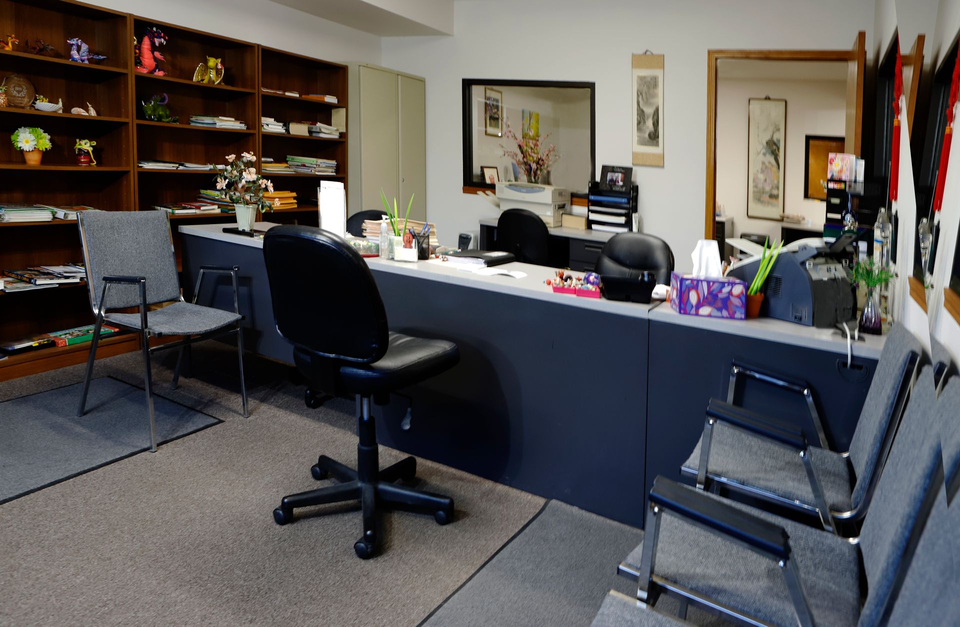 A waiting room with chairs and a desk with a box of tissues on it