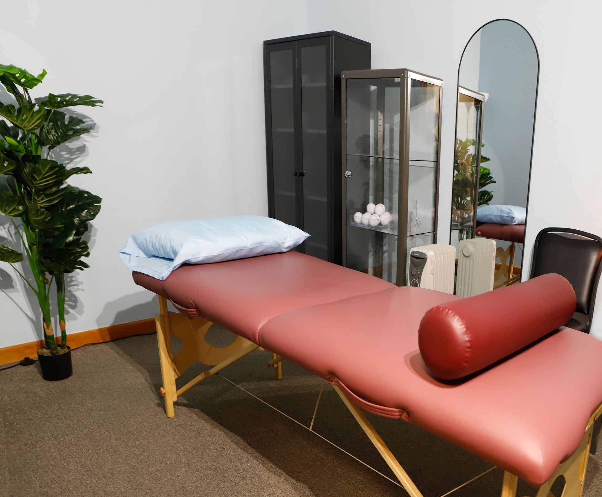 A massage table in a room with a mirror and a plant