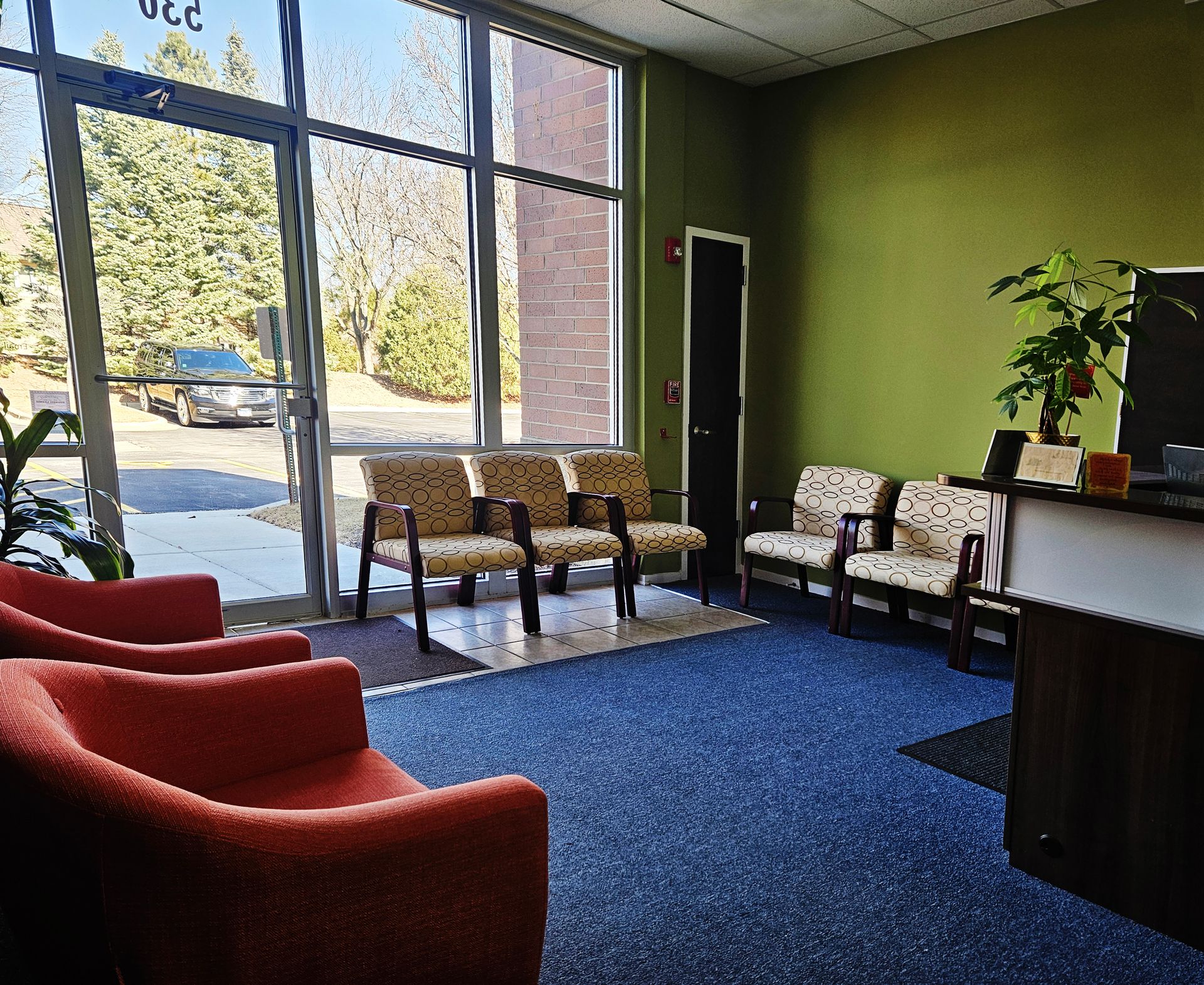 A waiting room with red chairs and a large window