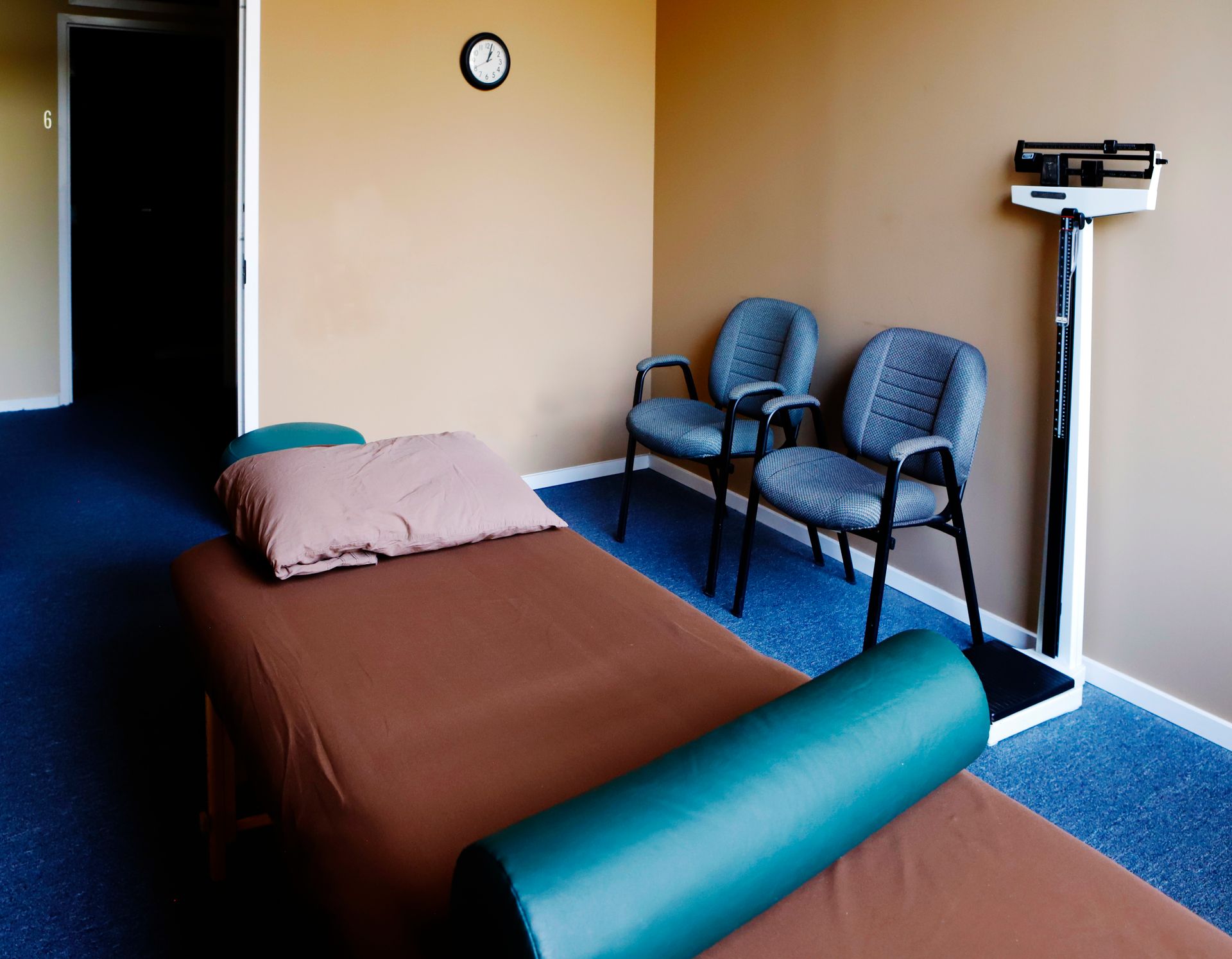A room with a bed and chairs and a scale on the wall