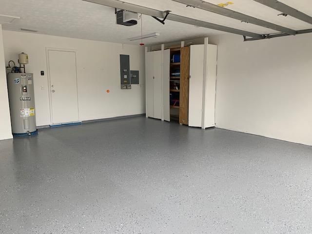 An empty garage with a water heater and cabinets.