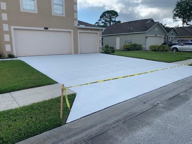 A white car is parked in a driveway next to a house.