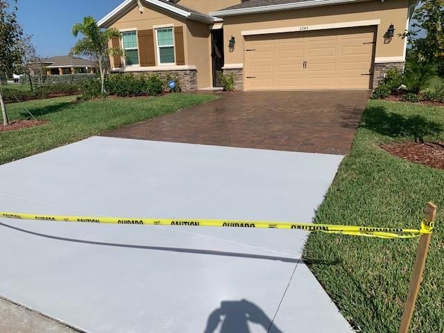A concrete driveway is being painted in front of a house