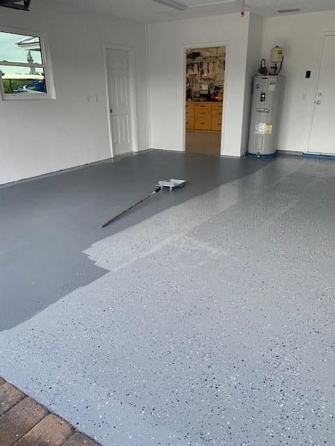 A garage floor is being painted with a brush.