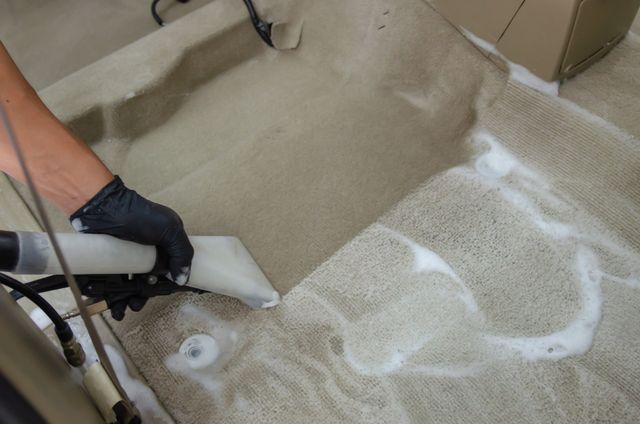 A professional cleaner using a vacuum to thoroughly clean carpets in a home.