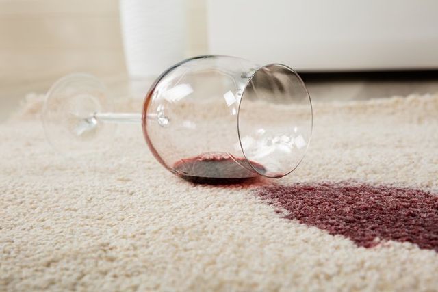 A glass of red wine spilled on a carpet.