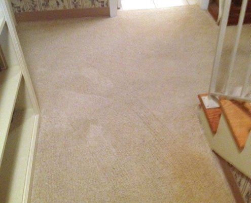 A carpeted hallway with stairs in a house, illustrating classic home features.