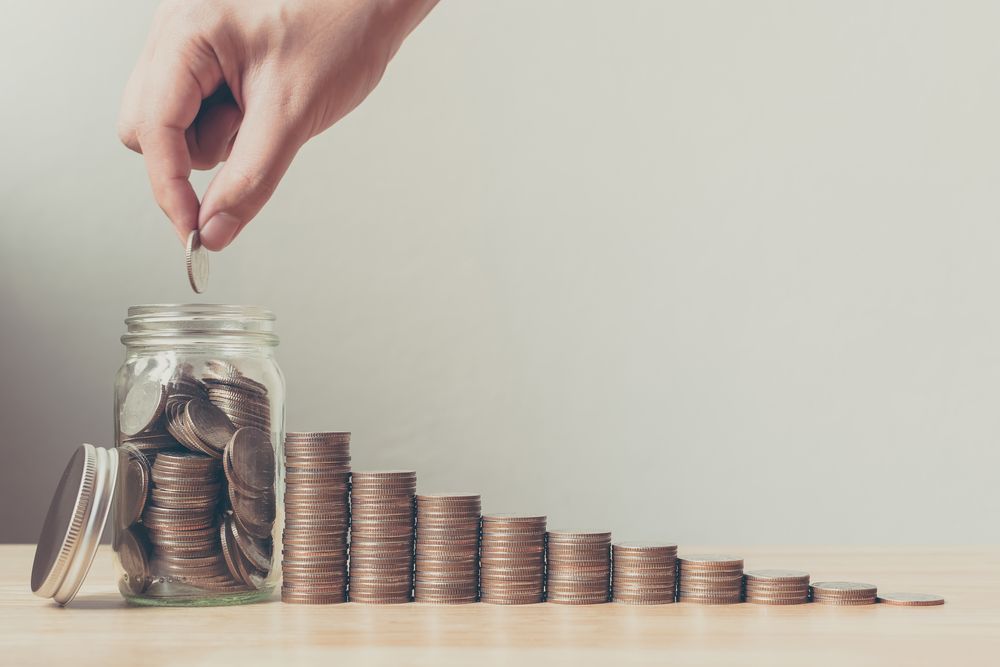 A Person Is Putting A Coin Into A Jar Of Coins — Simple Solutions Accounting In Bundaberg West, QLD