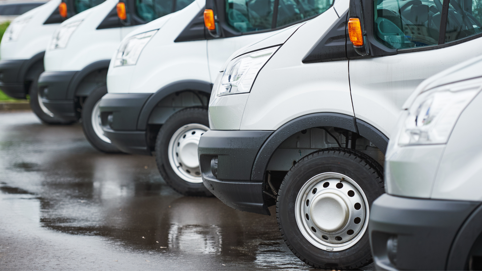 A row of white vans parked next to each other in a parking lot.